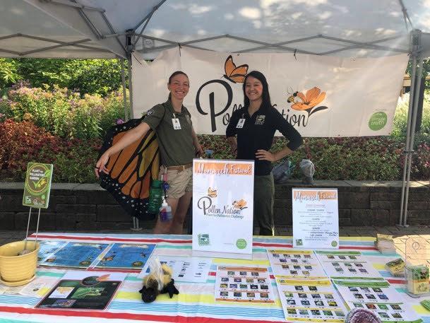 Americorps membersat a booth educating about pollinator, one member wearing butterfly wings