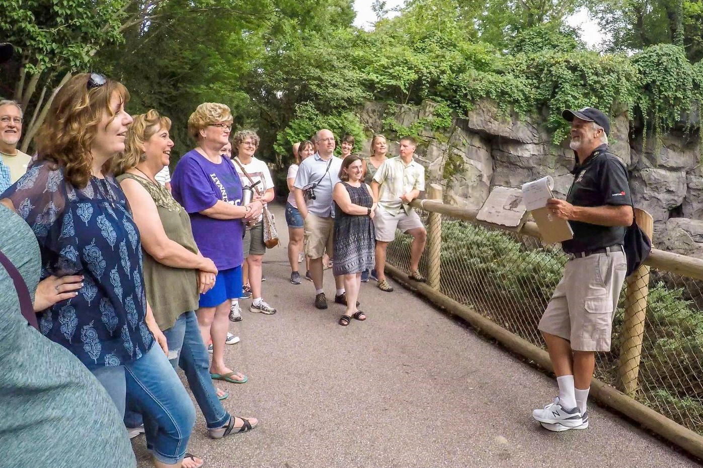 group of adults listen to Gary Denzler in front of animal habitat