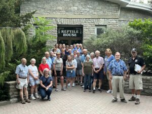 group of adults standing in front of the zoos reptile building
