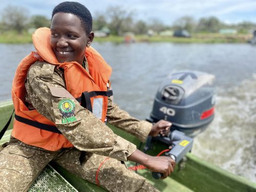 man with orange lifejacket in Uganda fishing boat on patrol
