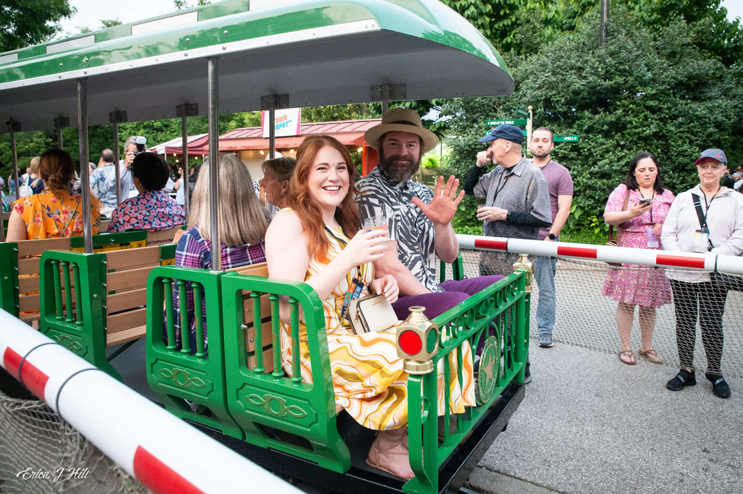 guests riding in the caboose of a green train during a zoo event