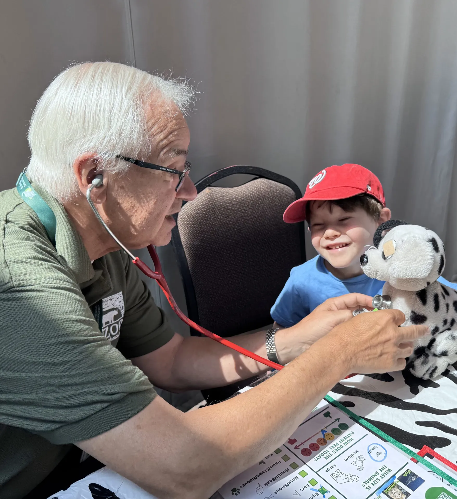 Stuffed animal clinic volunteer checking on a small smiling Childs dalmation stuffie