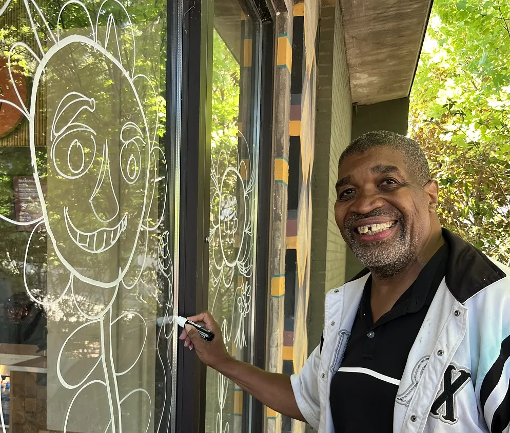 Artist Curtis Davis working on his mural at Mai Thai’s Marketplace.
